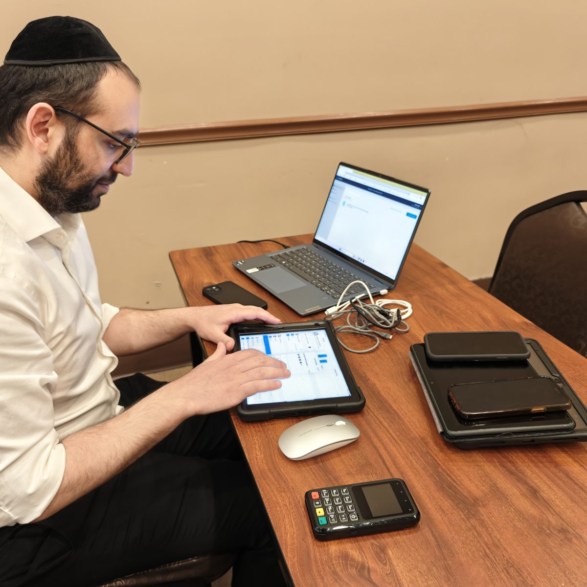 A Smart Connections NY team member setting up filtering on a tablet, with a laptop and devices on the desk